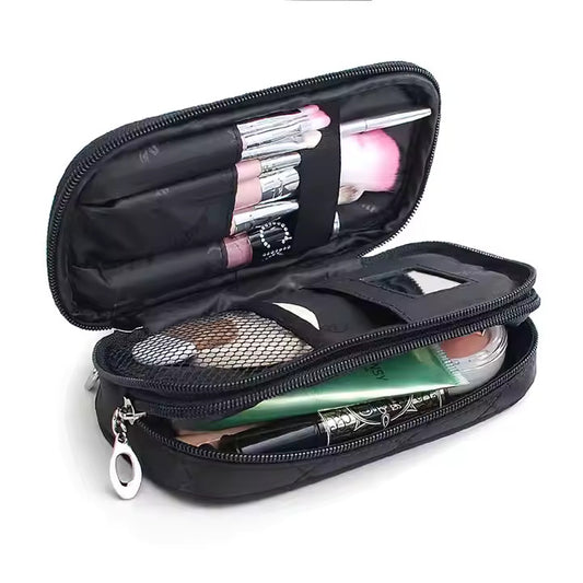 A black colored leather cosmetic bag having cosmetic items in it lying on a floor.